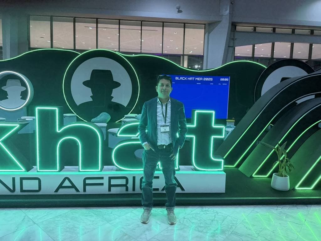 Aruneesh Salhotra in front of the Black Hat MEA 2025 neon sign