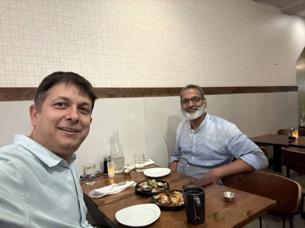 Aruneesh Salhotra with a colleague at a restaurant on the conference circuit