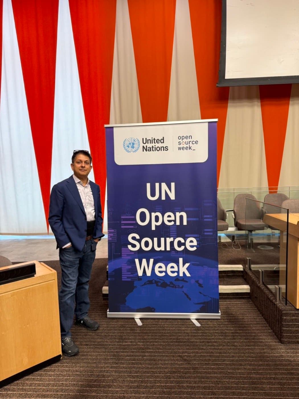 Aruneesh Salhotra beside the UN Open Source Week banner in a United Nations chamber